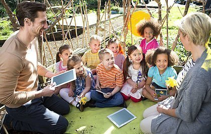Grundschulklasse mit Tablets beim Unterricht im Freien