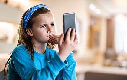 Mädchen schaut in ein Smartphone.