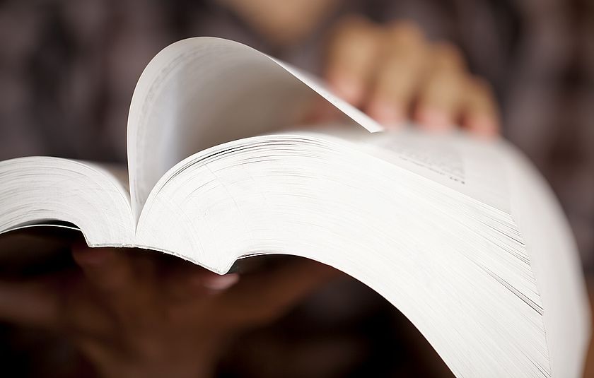 In einem dicken Buch wird eine Seite umgeblättert.