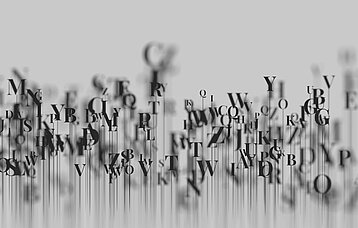 Schwarze Buchstaben vor grauem Hintergrund