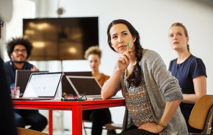 Vier Personen sitzen an einem Tisch mit Laptops