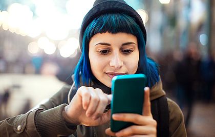 Mädchen mit blauen Haaren am Smartphone.