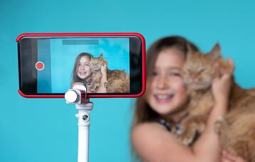 Mädchen posiert mit einer Katze für ein Smartphone-Video