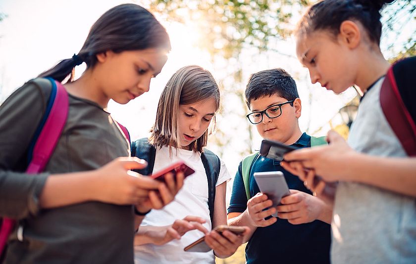 Schülerinnen und Schüler mit Blick in ihre Handys.