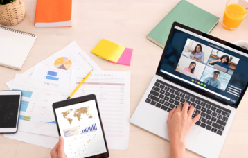 Schreibtisch mit Laptop und Tablet, an dem eine Person arbeitet