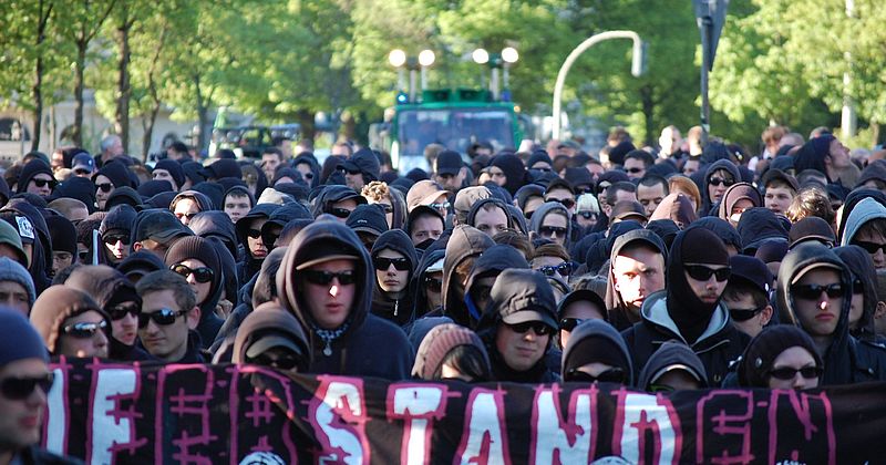 Gruppenbild von Menschen in schwarzen Hoodies mit einem Banner mit dem Slogan "Auferstanden".