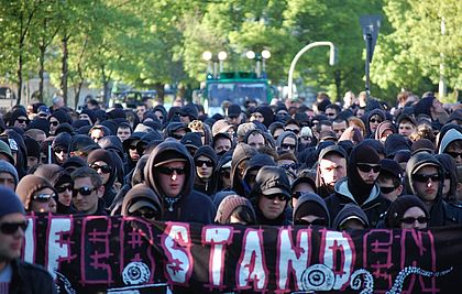 Gruppenbild von Menschen in schwarzen Hoodies mit einem Banner mit dem Slogan "Auferstanden".