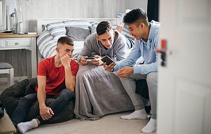 Jugendliche zuhause im Zimmer mit Blick in ihr Smartphone.