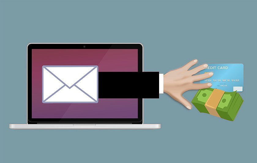 Aus einem Bildschirm greift eine Hand nach Geld und Kreditkarte