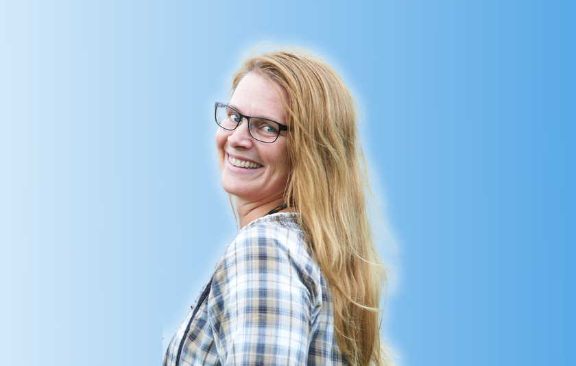 Frau mittleren Alters mit hellroten langen Haaren und Brille in weiß-blau-braun kariertem Hemd