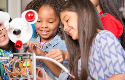 Schülerinnen arbeiten mit Roboter