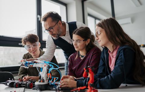 Schülerinnen, Schüler und Lehrkraft arbeiten an einem Robotik-Projekt im Unterricht