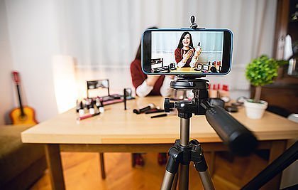 Handykamera mit Stativ filmt eine Frau bei der Vorstellung von Kosmetik