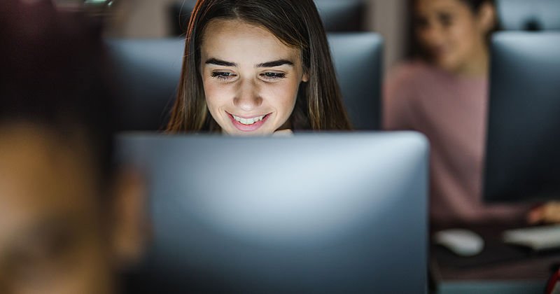 Lächelnde Schülerin vor ihrem PC in einer Computerklasse.