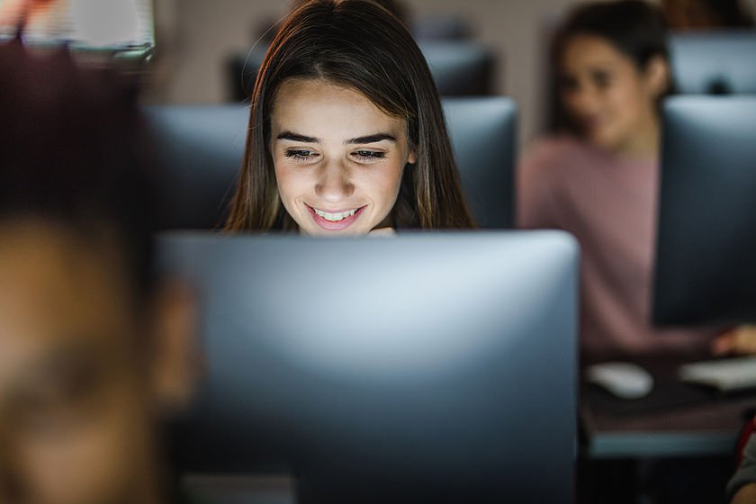 Lächelnde Schülerin vor ihrem PC in einer Computerklasse.