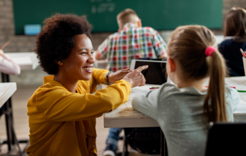 Eine Lehrerin, die einer Schülerin im Unterricht etwas auf dem iPad zeigt