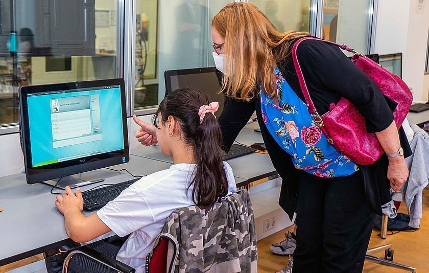 Isabell Fezer hinter einem Mädchen am Computer bei der Sommerschule am SMZ Stuttgart
