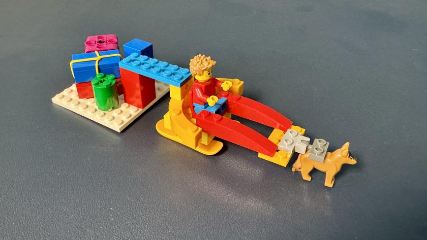 LEGO-Modell: ein Schlitten, auf dem eine Figur sitzt, der von einem Tier gezogen wird.