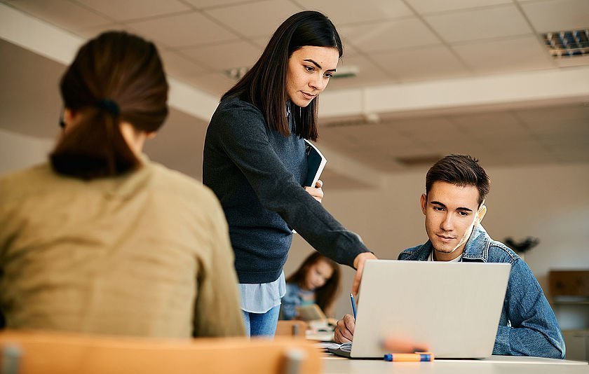 Gymnasiallehrerin erklärt ihrem Schüler einen Sachverhalt am Notebook.