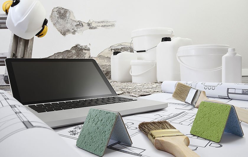 Das Foto zeigt ein Notebook und etliche Gerätschaften wie wie Pinsel und Farbeimer.