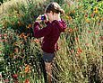 Grundschülerin mit Kamera in einer Blumenwiese