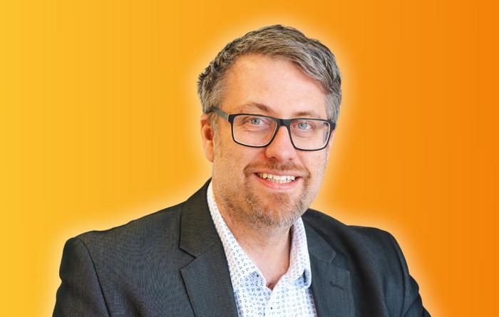 Mann mittleren Alters mit grau meliertem Haar, Brille und dunkelgrauem Sakko.