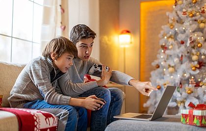Zwei Jungs sitzen neben dem Weihnachtsbaum am Laptop