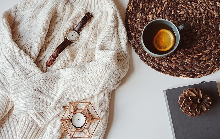 Stillleben Pullover, Tee, Tannenzapfen und Kerze auf einem Tisch Stillleben Pullover, Tee, Tannenzapfen und Kerze auf einem Tisch