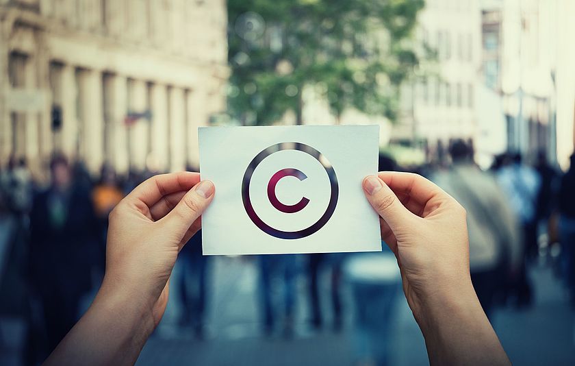 Zwei Hände halten ein Blatt Papier mit dem Copyright-Zeichen in die Höhe. 