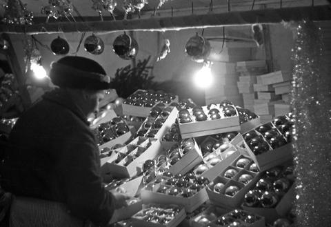 Schwarzweiß-Foto einer Weihnachtsmarktbude mit Christbaumschmuck in Stuttgart im Jahr 1938.
