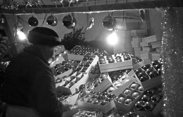 Schwarzweiß-Foto einer Weihnachtsmarktbude mit Christbaumschmuck in Stuttgart im Jahr 1938.