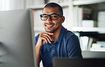 Junger Mann mit Brille am PC