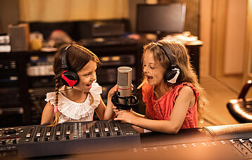 Zwei kleine Mädchen in einem Tonstudio mit Kopfhörern