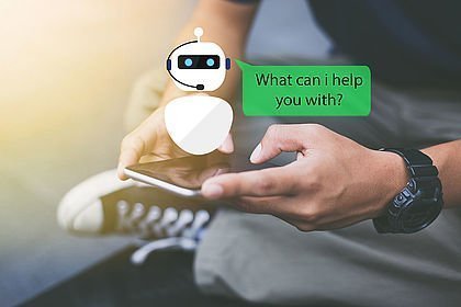 Hand mit Smartphone und eingeblendetem Chatbot