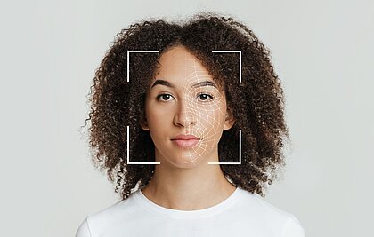 Das Gesicht einer Frau wird abgescannt, was auf dem Foto durch ein Netz und einen Rahmen angezeigt wird.