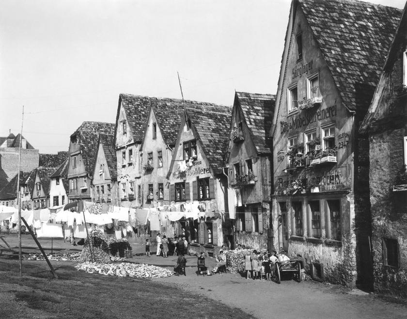 Es zeigt Häuser und das lebhafte Treiben der Menschen am Flussufer der Enz im Jahr 1933.