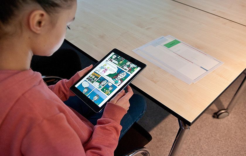 Mädchen schaut ein Comic auf einem Tablet