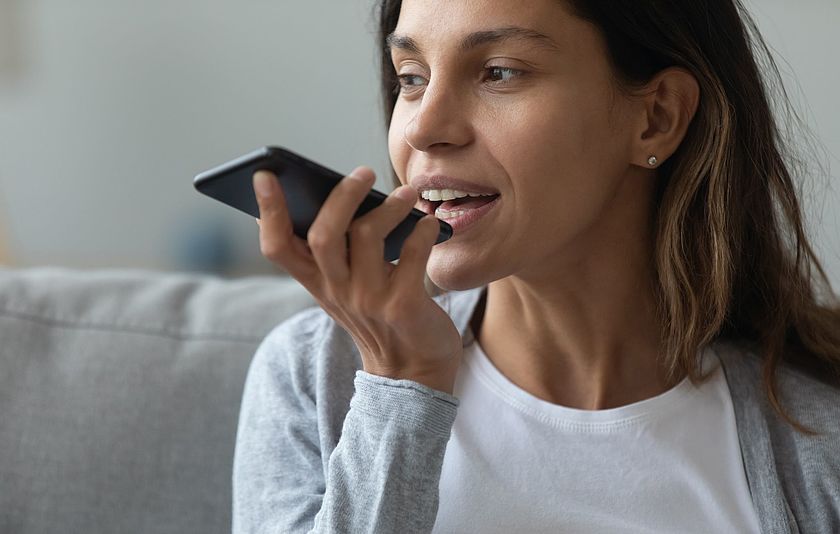 Junge Frau spricht in ihr Smartphone.