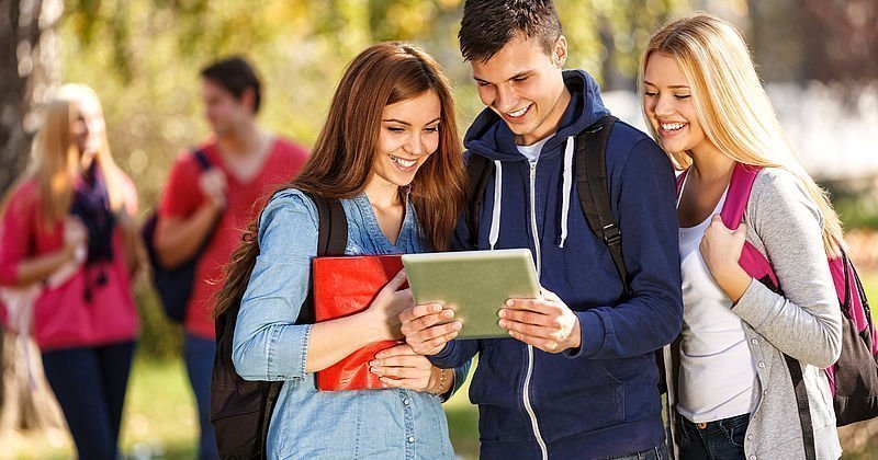 Drei Teenager sehen auf ein Tablet