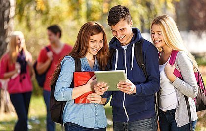 Drei Teenager sehen auf ein Tablet