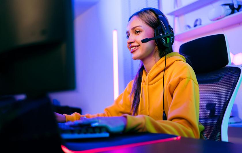 Teenager-Mädchen mit Headset sitzt an einem Gaming-Computer und auf einem Gaming-Stuhl.