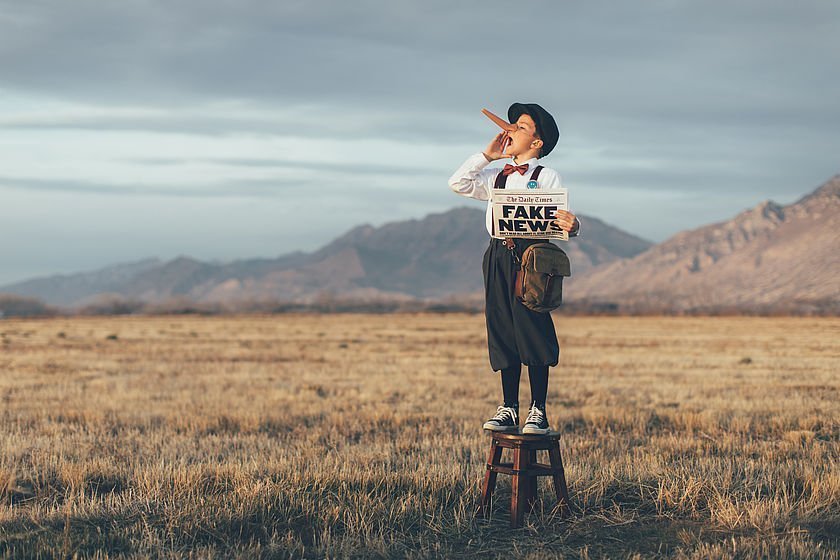 Junge mit Fake-News-Zeitung und Pinocchio-Nase Junge mit Fake-News-Zeitung und Pinocchio-Nase