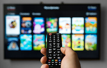 Hand hält Fernbedienung für einen Smart TV