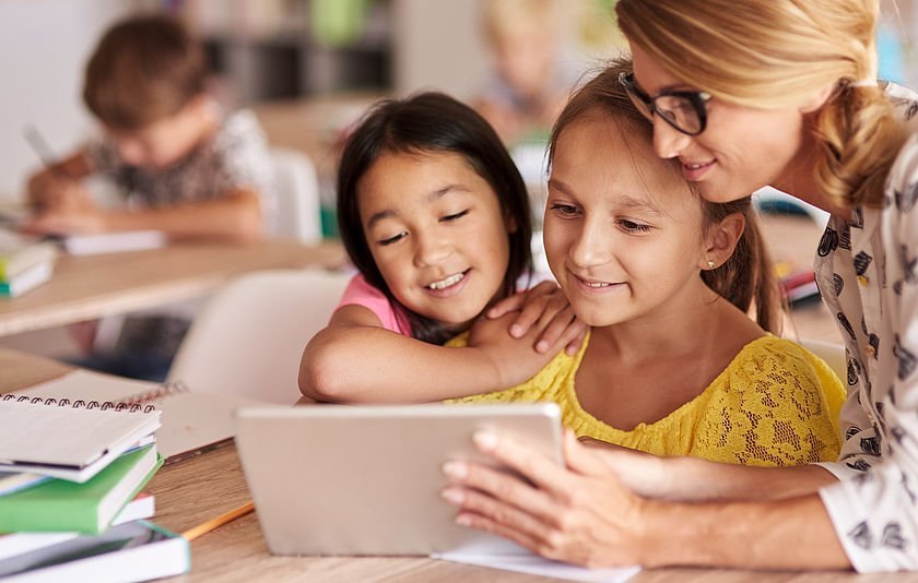 Lehrerin mit Grundschülerinnen am Tablet Lehrerin mit Grundschülerinnen am Tablet