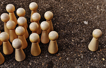 Gruppe Spielfiguren stehen einer einzelnen Spielfigur gegenüber