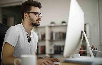 Junger Mann vor einem großen PC-Bildschirm
