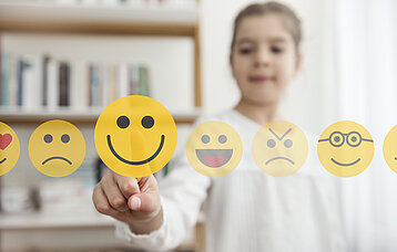 Mädchen vor einem Touchscreen mit unterschiedlichen Emojis