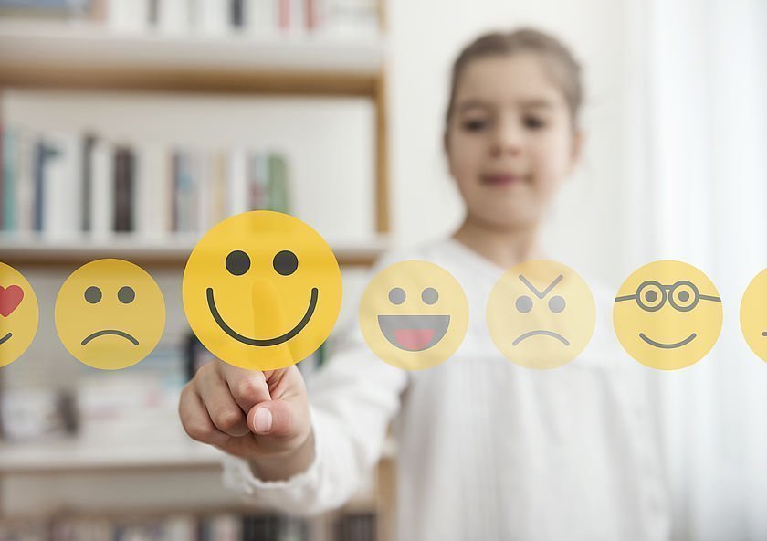 Mädchen vor einem Touchscreen mit unterschiedlichen Emojis