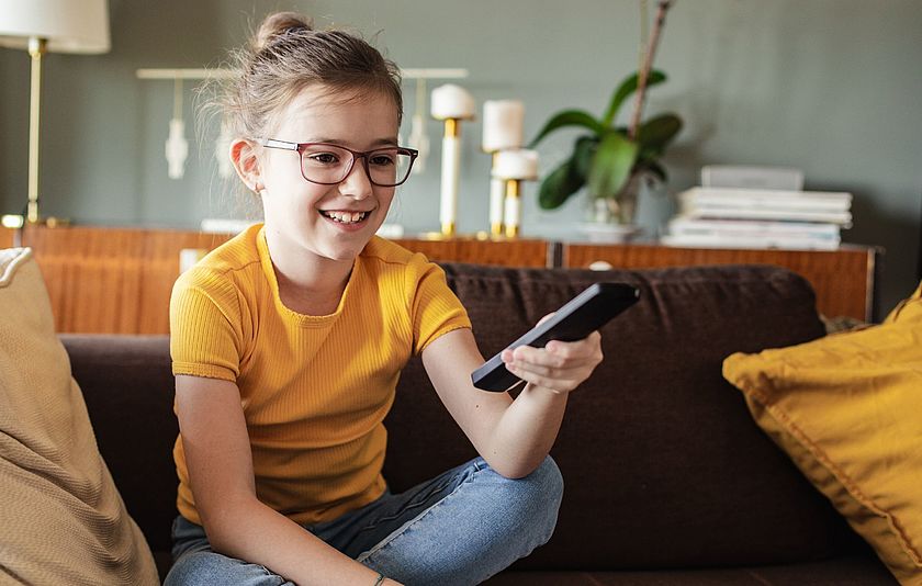 Mädchen mit Fernbedienung in der Hand.