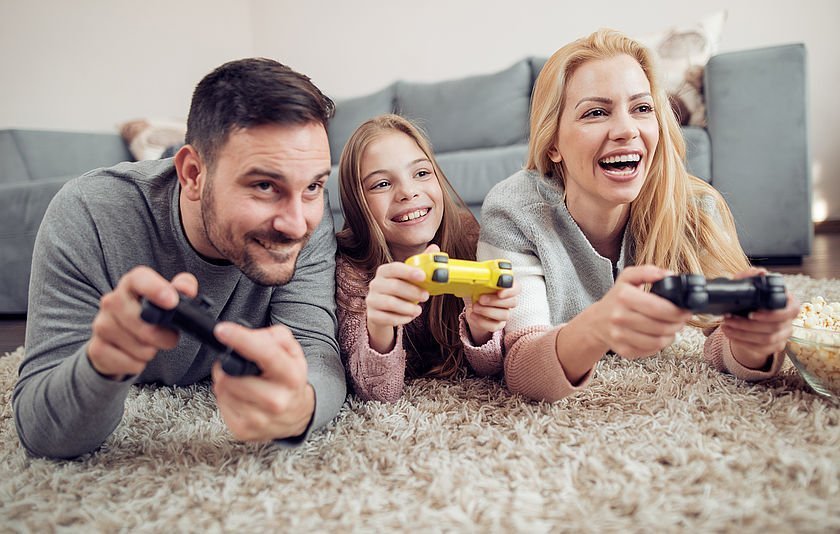 Familie liegt auf dem Boden und halten Game-Controller in den Händen Familie liegt auf dem Boden und halten Game-Controller in den Händen